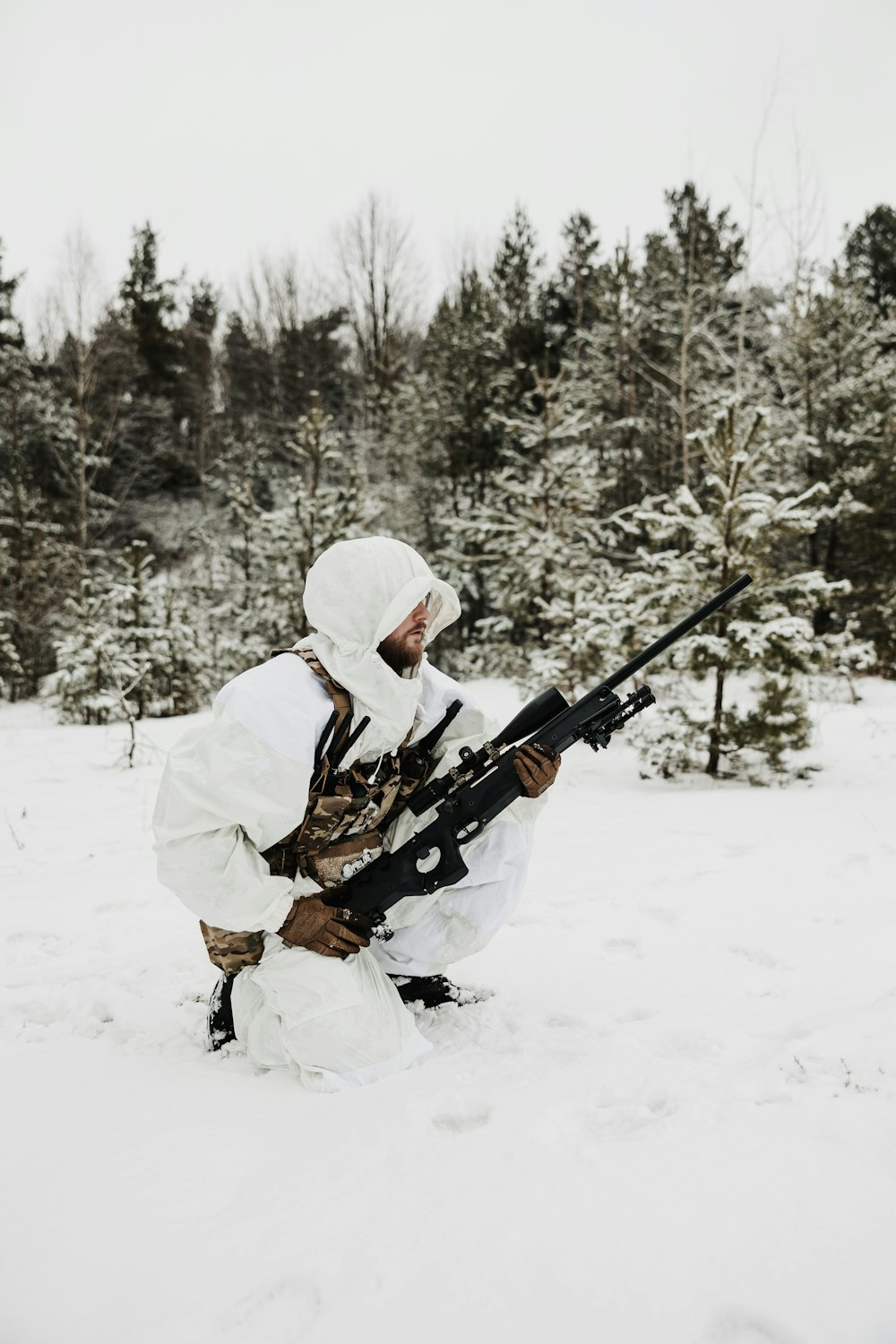 a man kneeling in the snow holding a rifle
