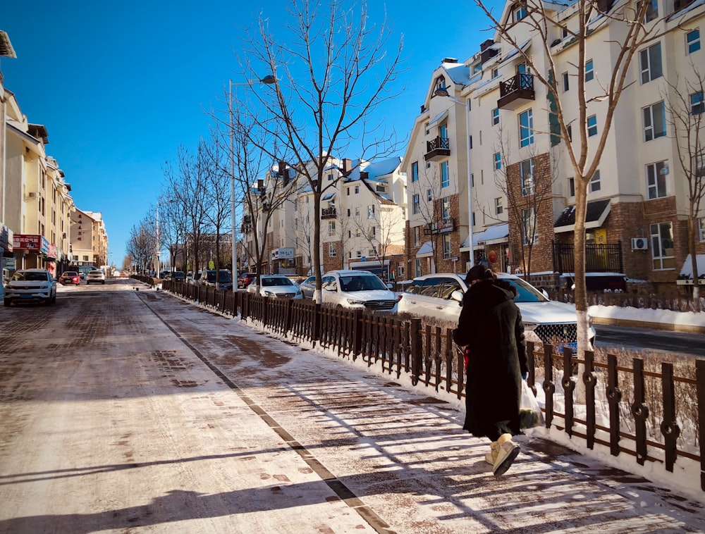 a man walking down a street next to tall buildings