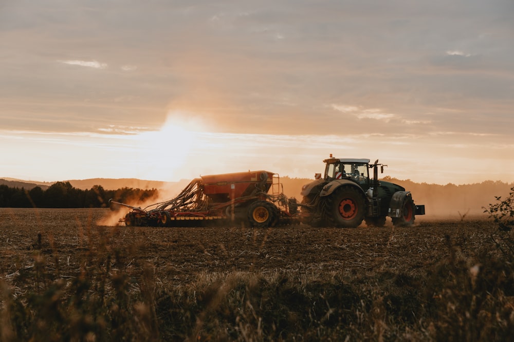 a tractor is driving through a field at sunset