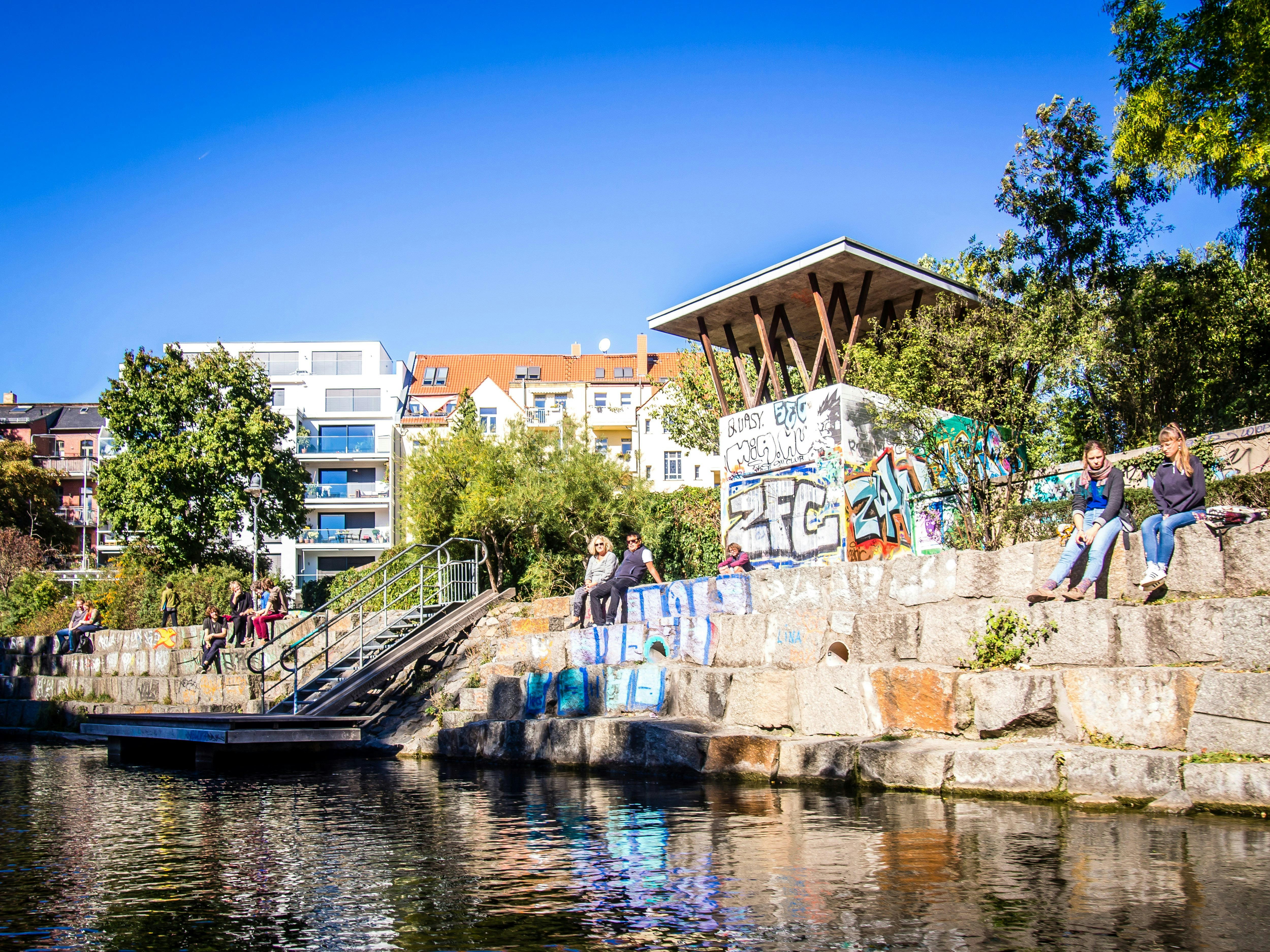 a group of people sitting on the side of a river