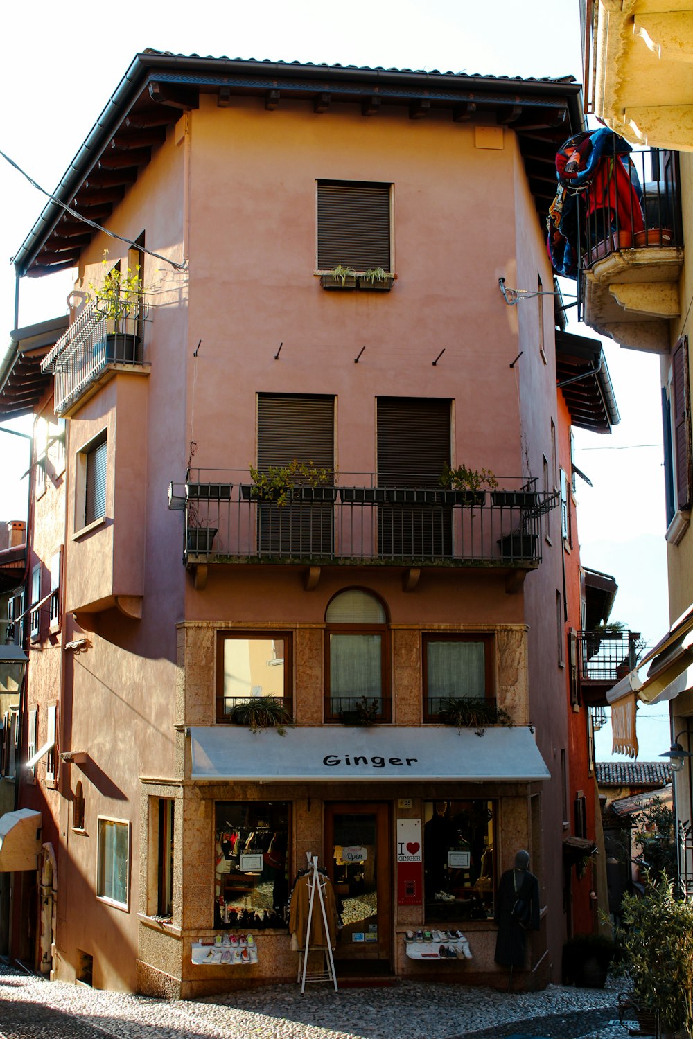 a pink building with a balcony and a store front