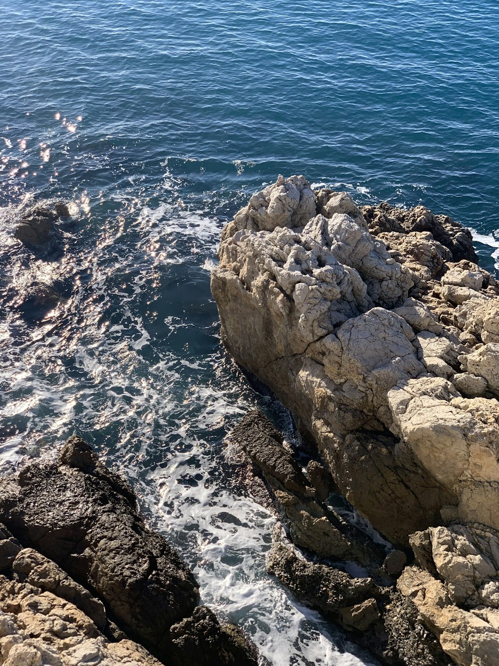 a man sitting on top of a rock next to the ocean