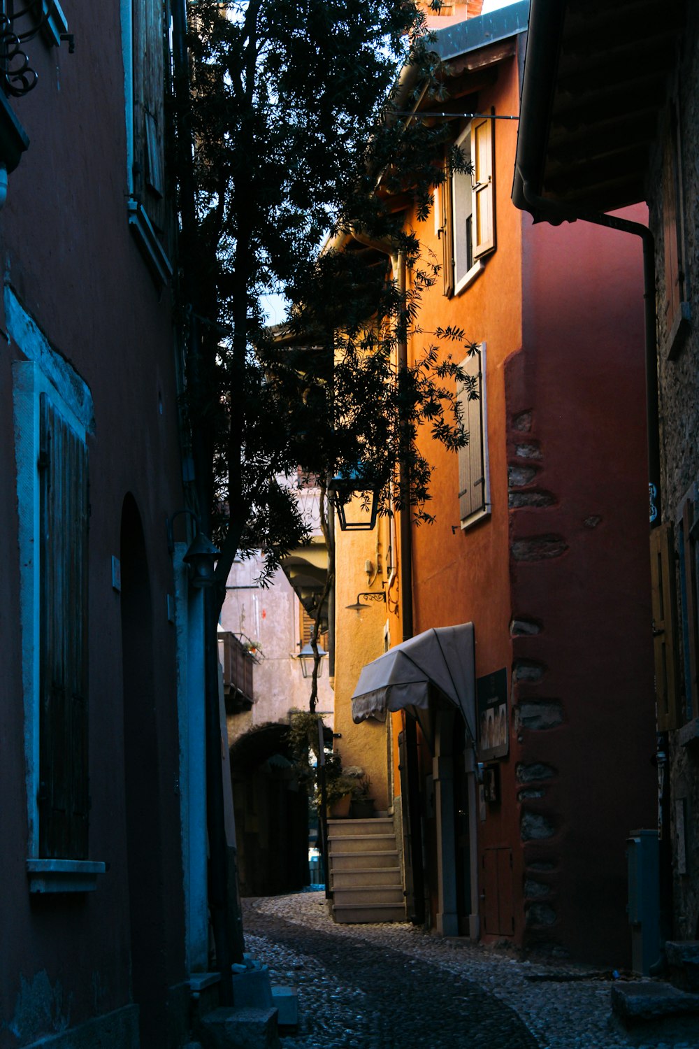 a narrow alleyway with an umbrella on a sunny day