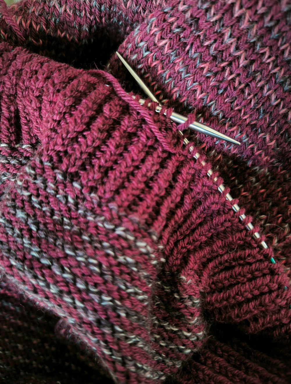 a close up of a knitted sweater with a pair of scissors