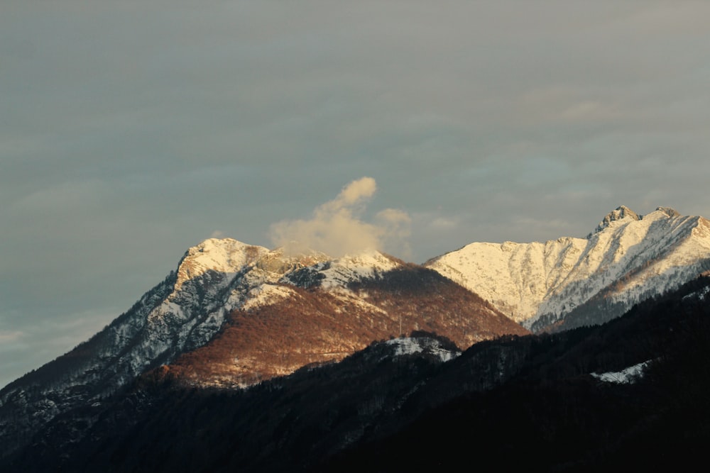 a snow covered mountain range under a cloudy sky