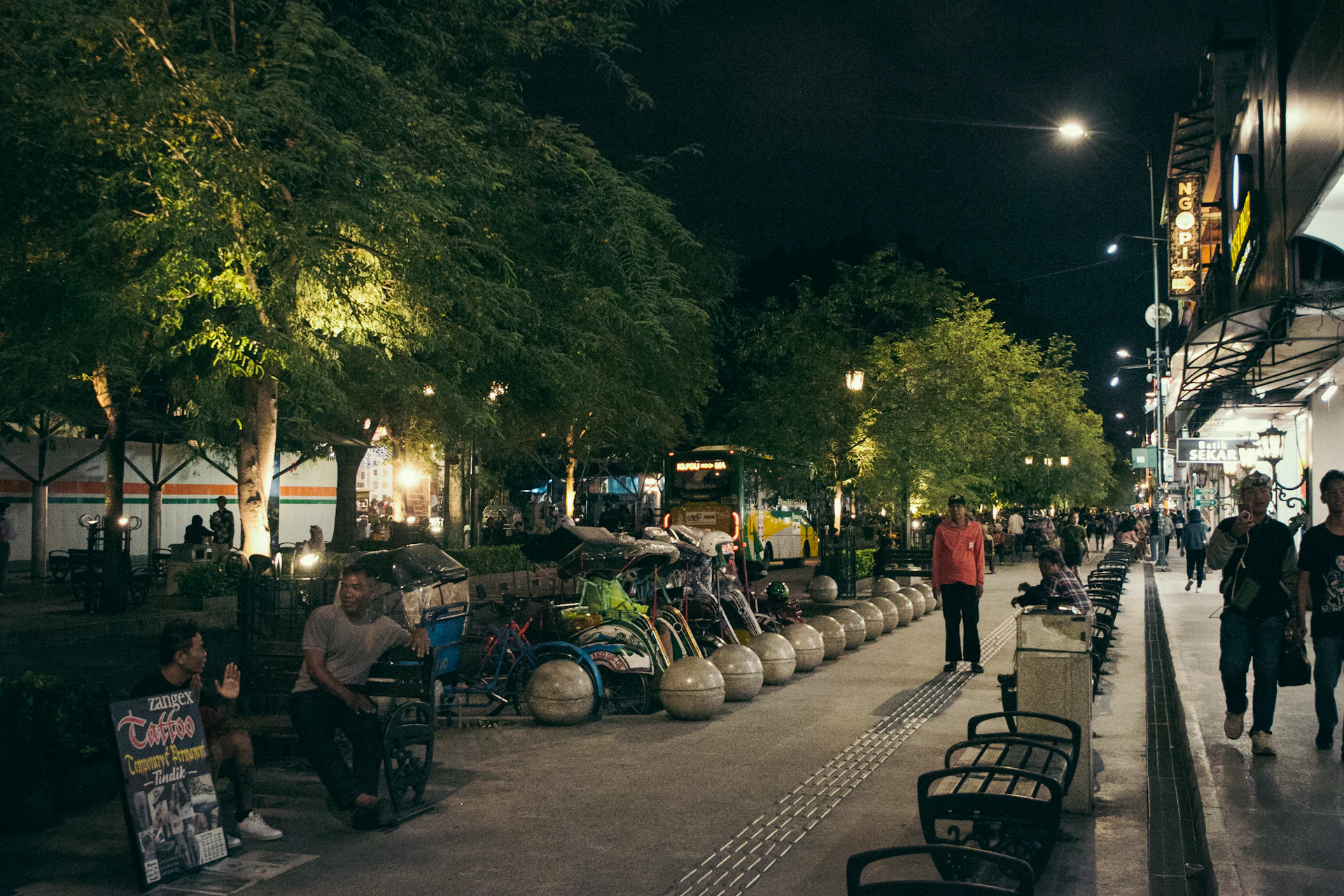 a group of people walking down a street at night