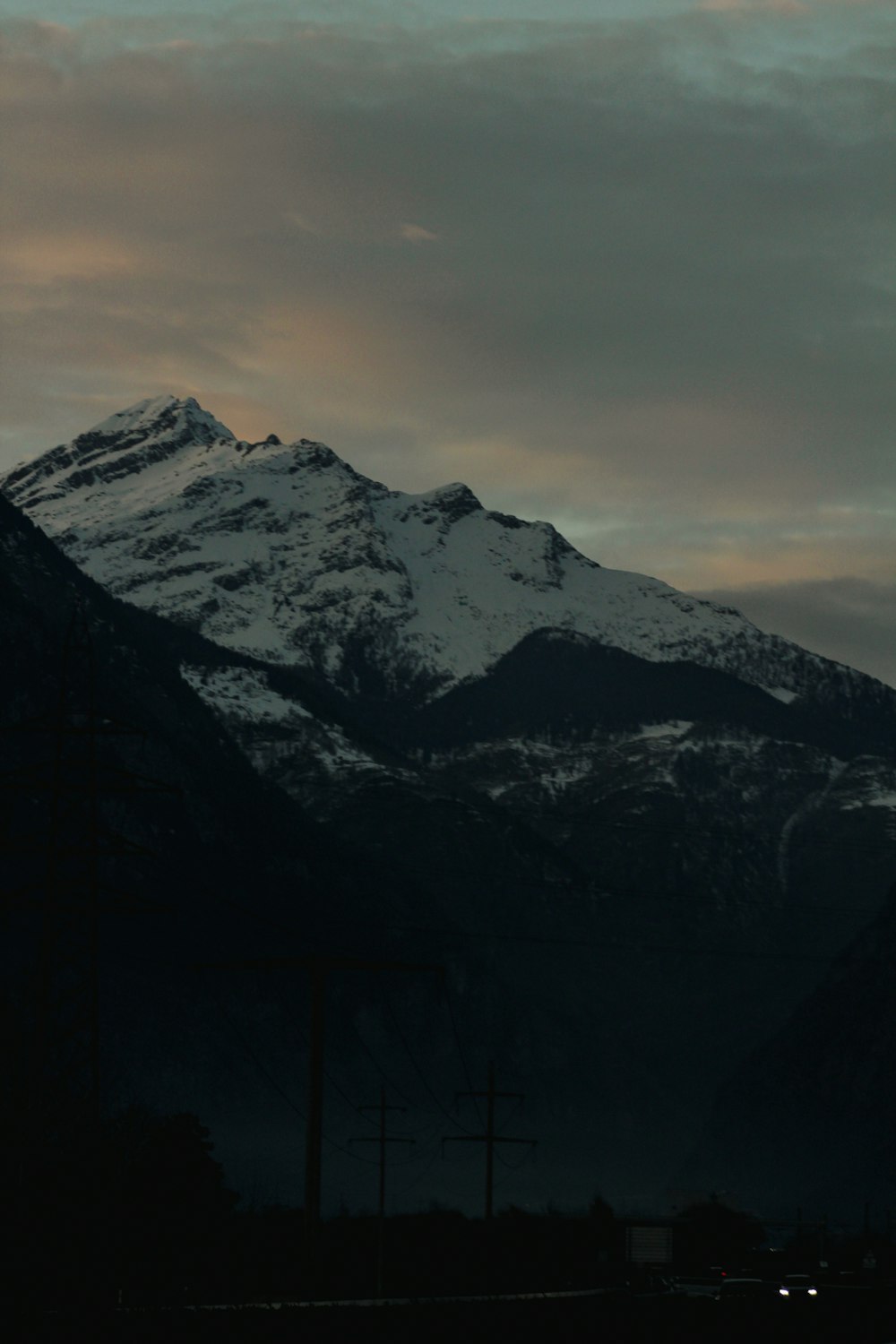 a large mountain covered in snow under a cloudy sky