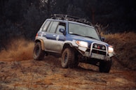 a blue four door suv driving on a dirt road