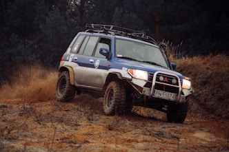 a blue four door suv driving on a dirt road