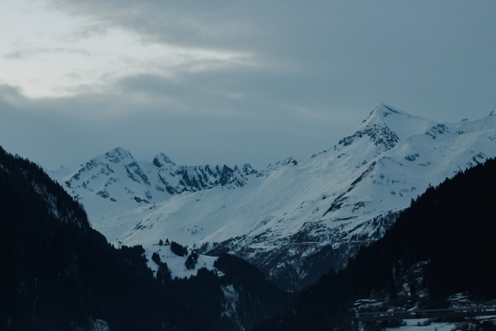 a snowy mountain range with a few trees in the foreground