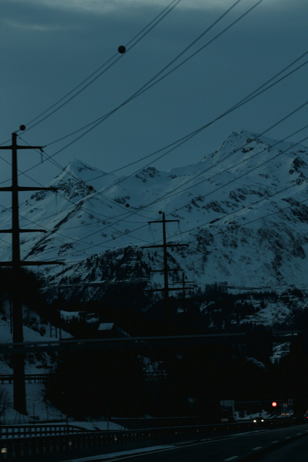 a view of a snow covered mountain with power lines in the foreground