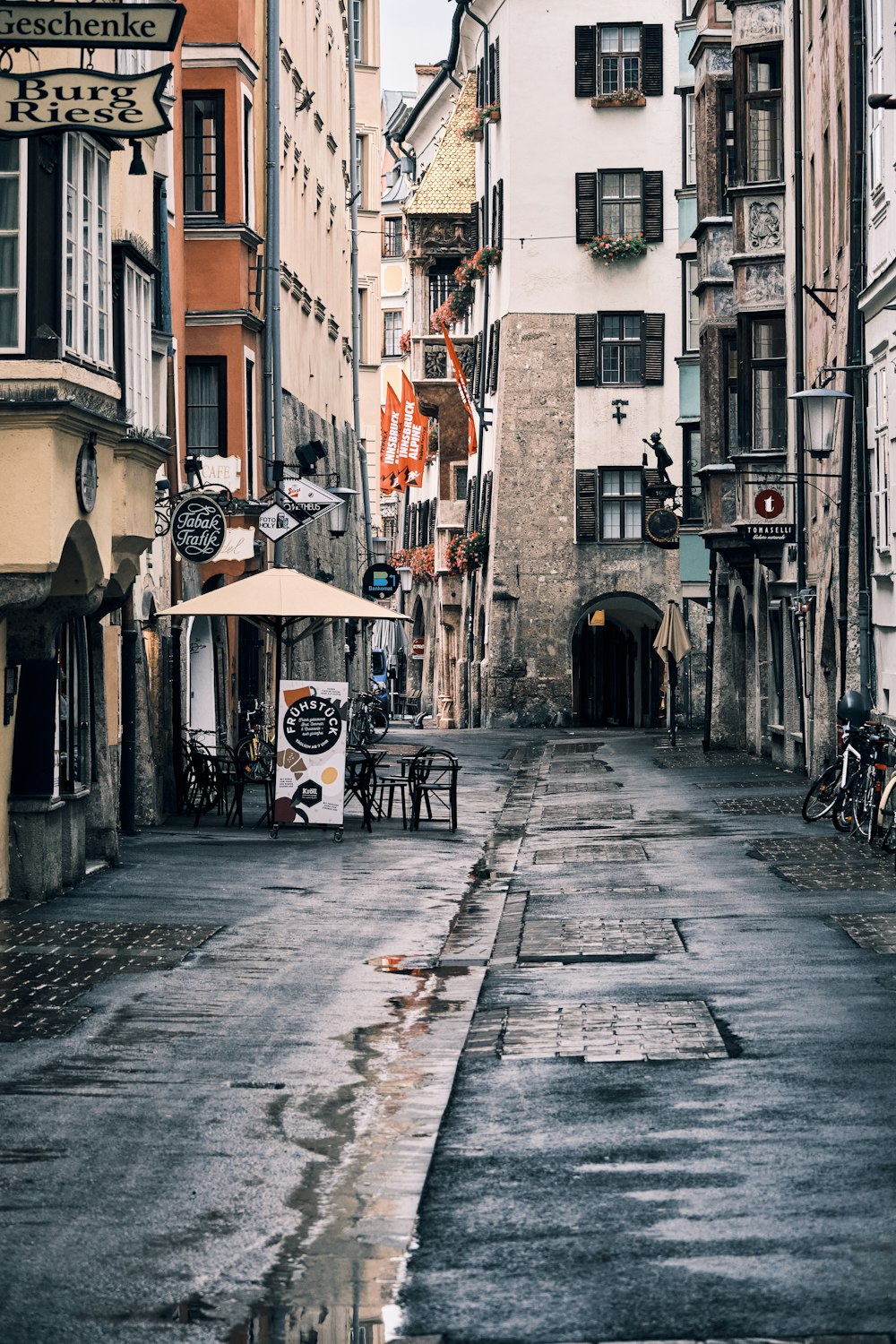 a narrow city street with tables and umbrellas