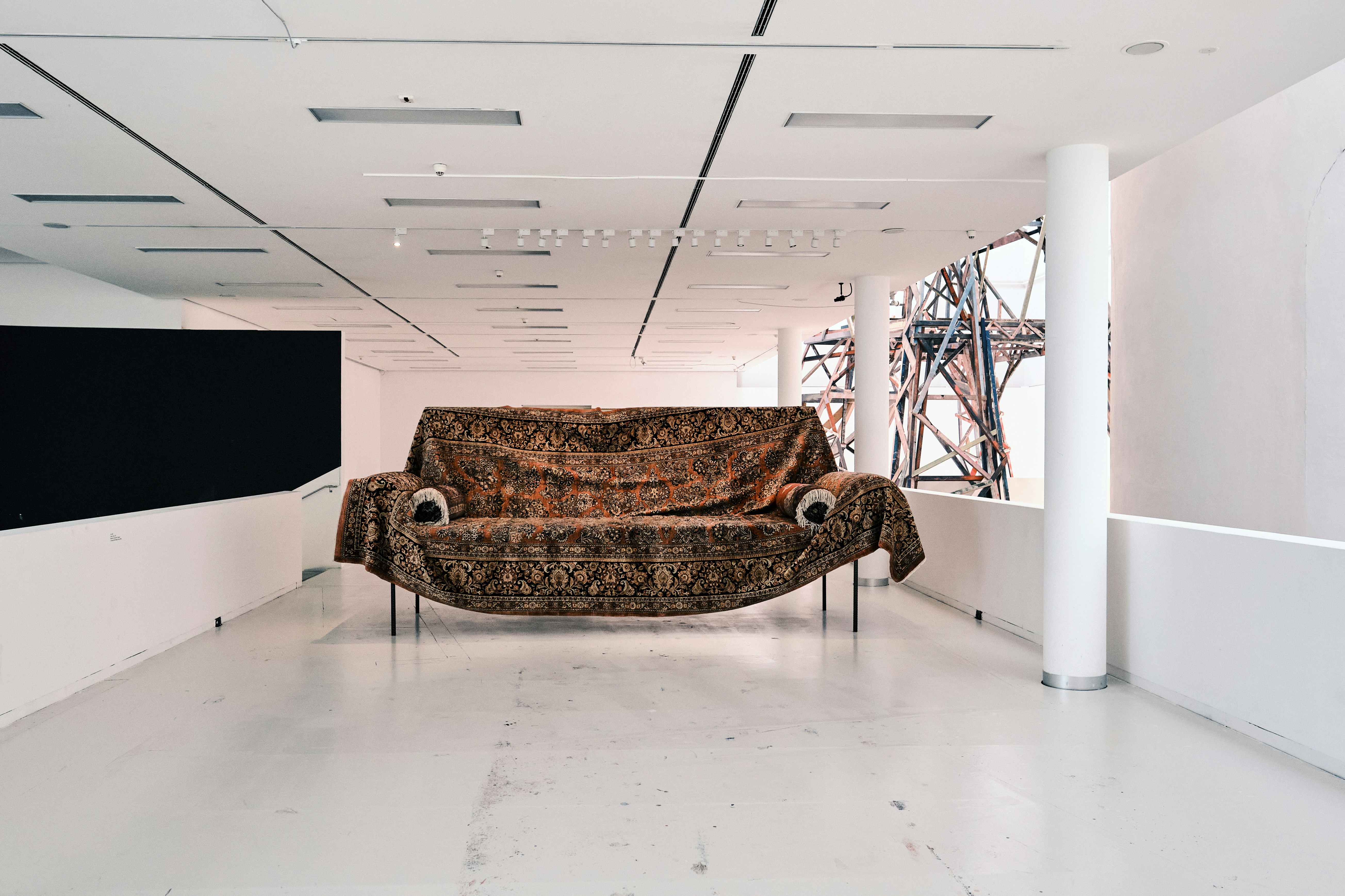 Couch draped in a blanket in an empty white room