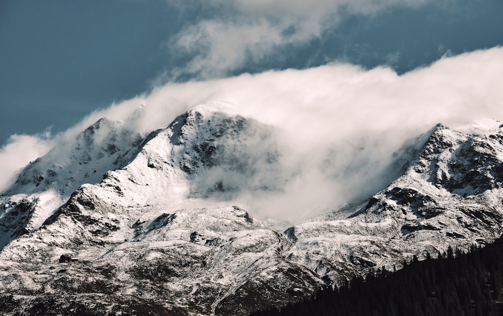 a mountain covered in snow under a cloudy sky