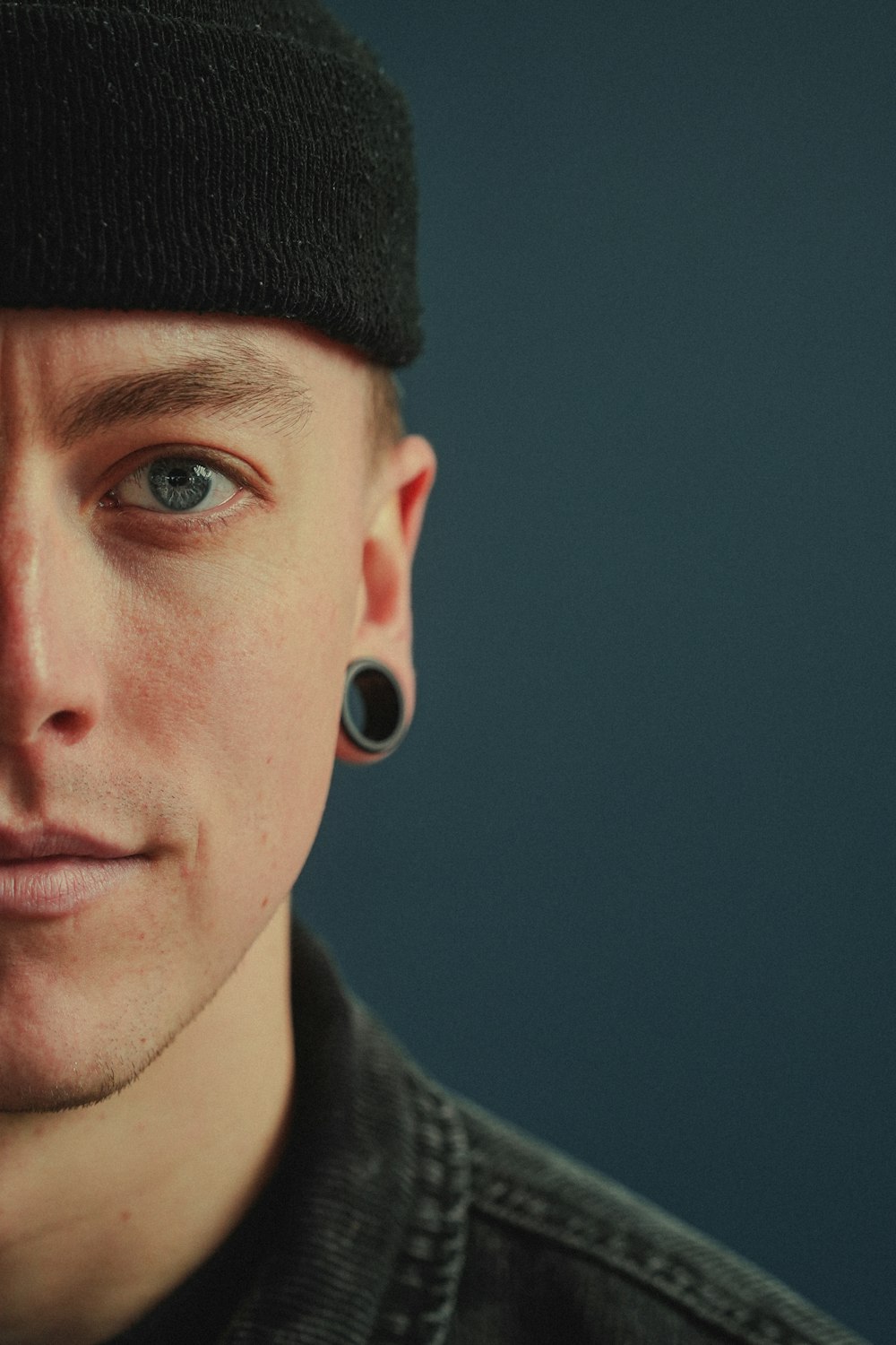 a man wearing a black hat and a pair of ear piercings