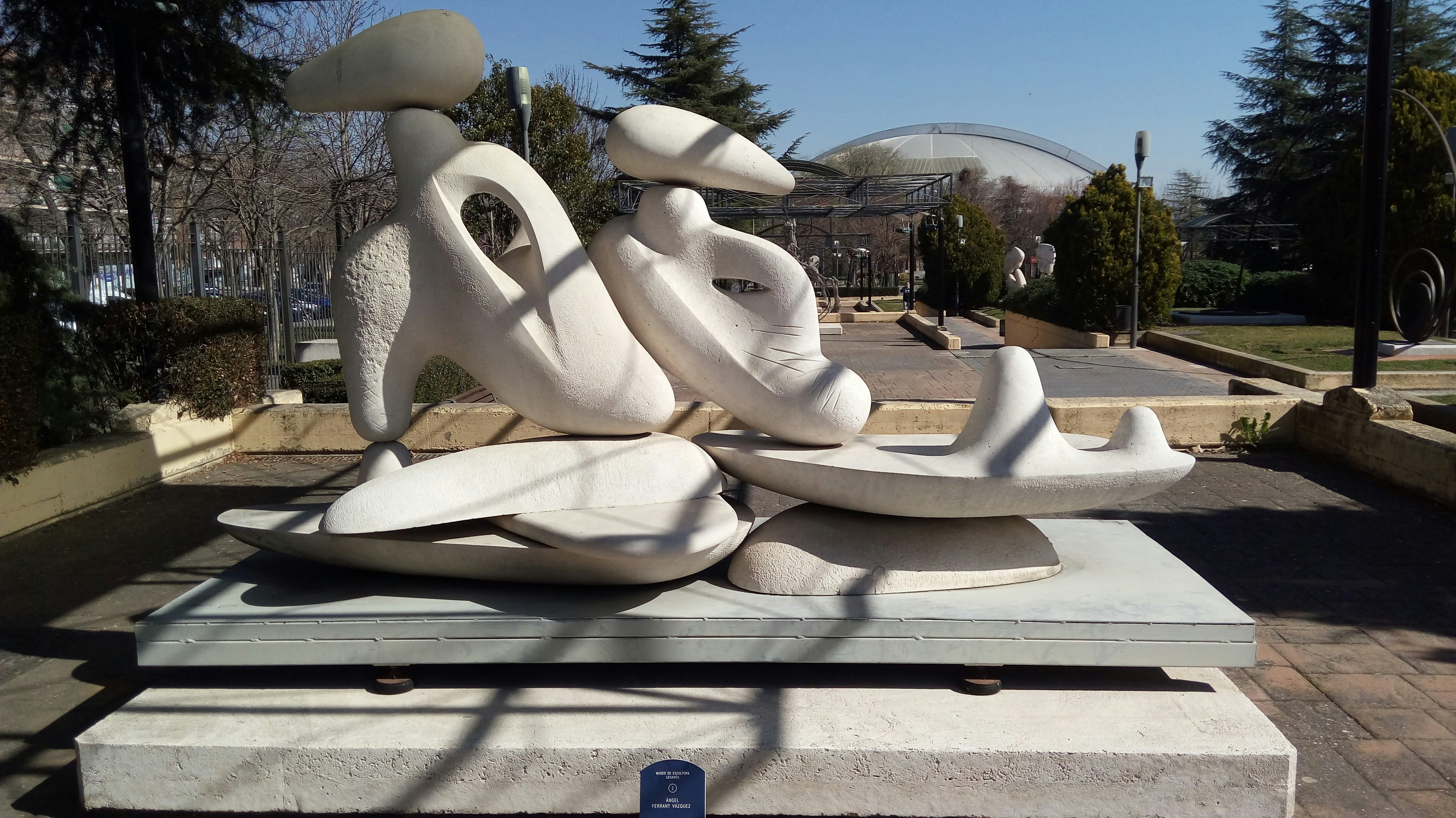 a sculpture of a bird on a rock in the middle of a park
