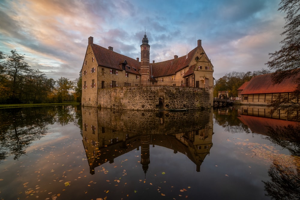 a castle sitting on top of a lake next to a forest