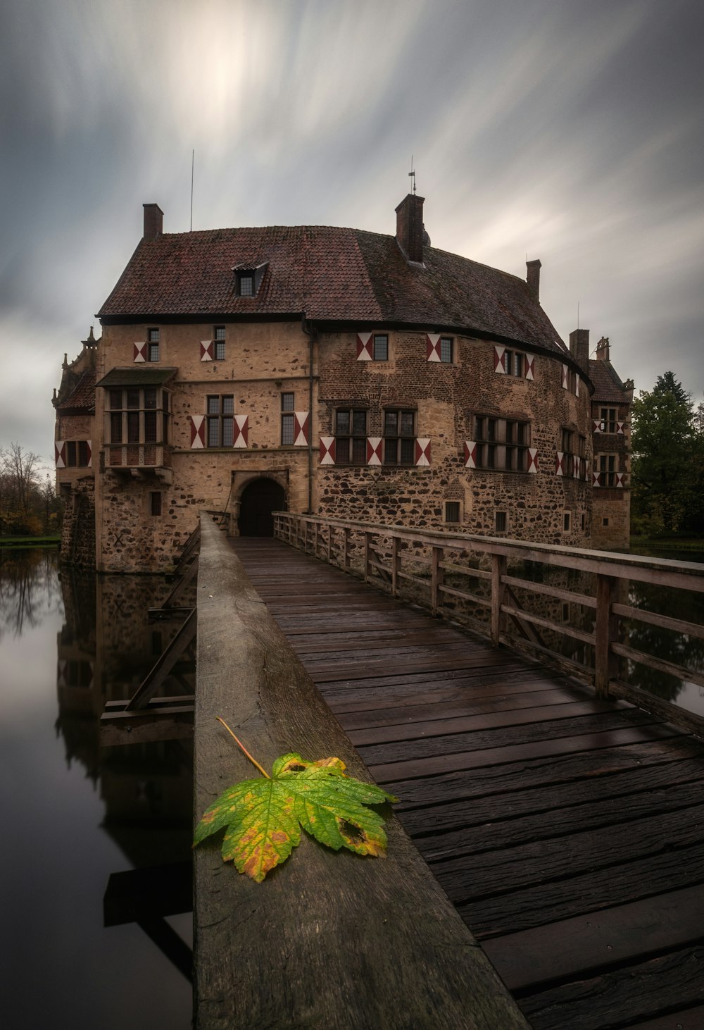 a leaf laying on a wooden bridge over a body of water