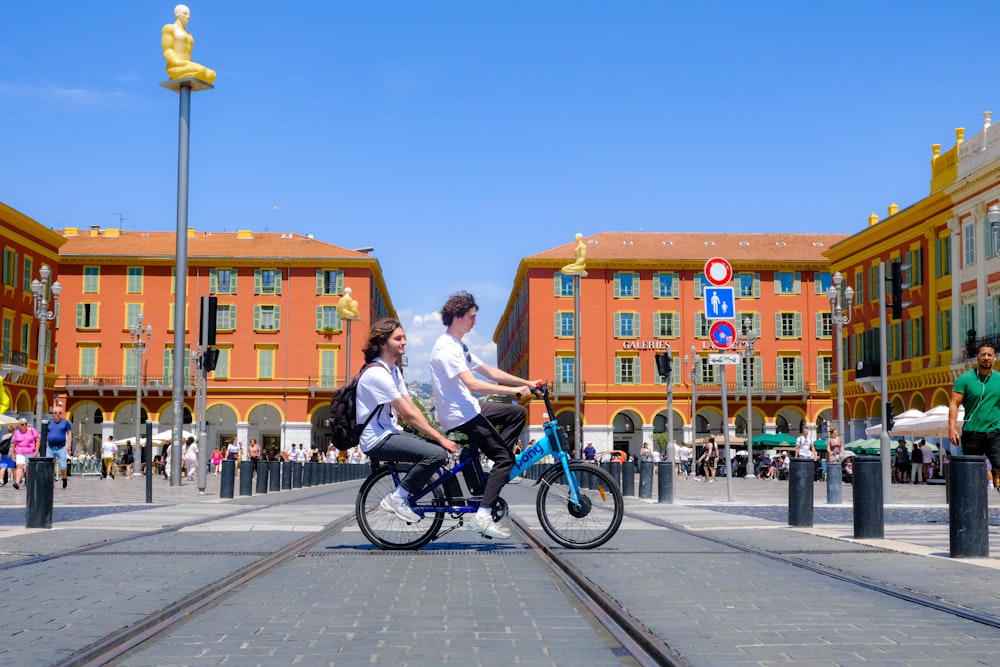 a man and a woman riding a bike in front of a building