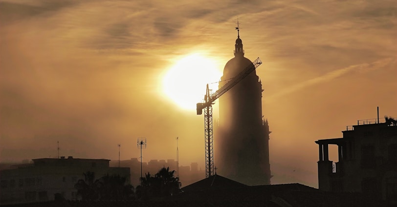 the sun is setting behind a tall building