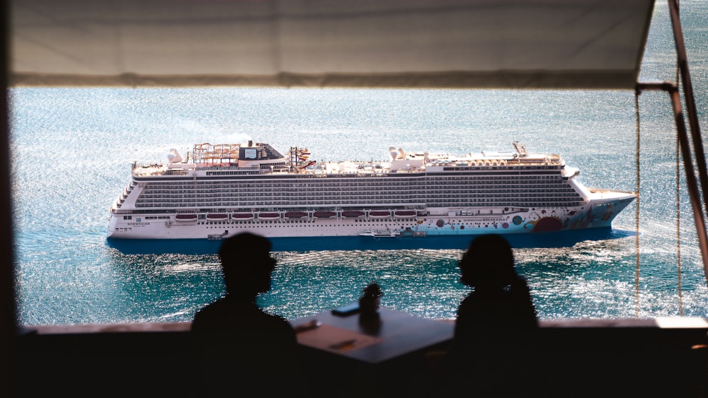 a cruise ship in the water with two people looking at it