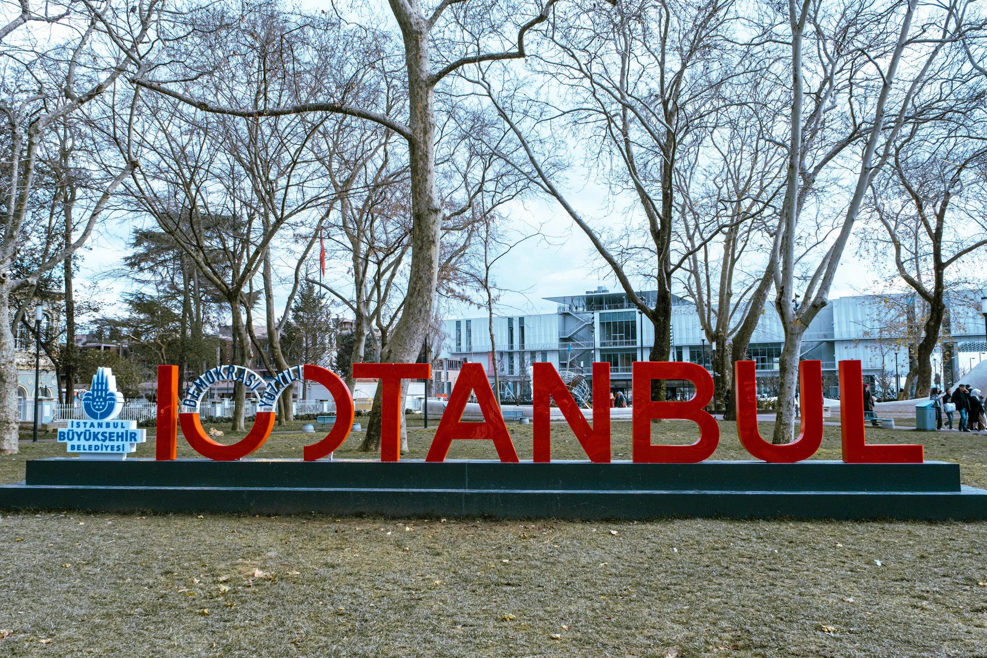 a large red sign sitting in the middle of a park