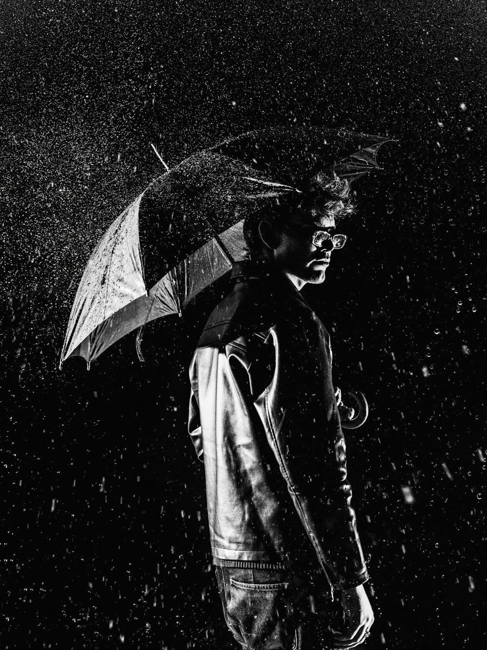 Un hombre de pie bajo la lluvia sosteniendo un paraguas