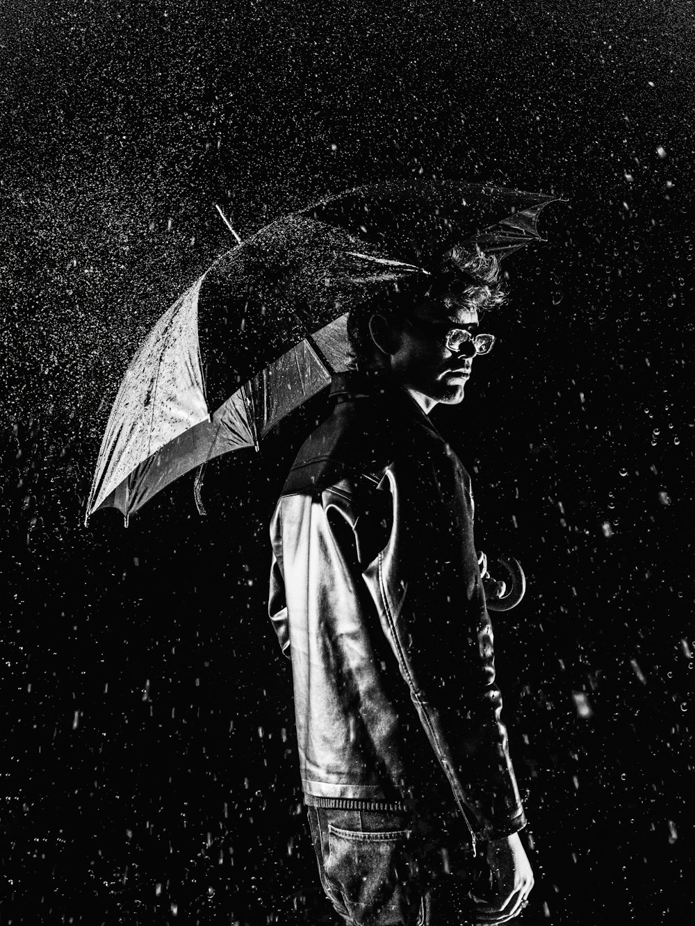 a man standing in the rain holding an umbrella