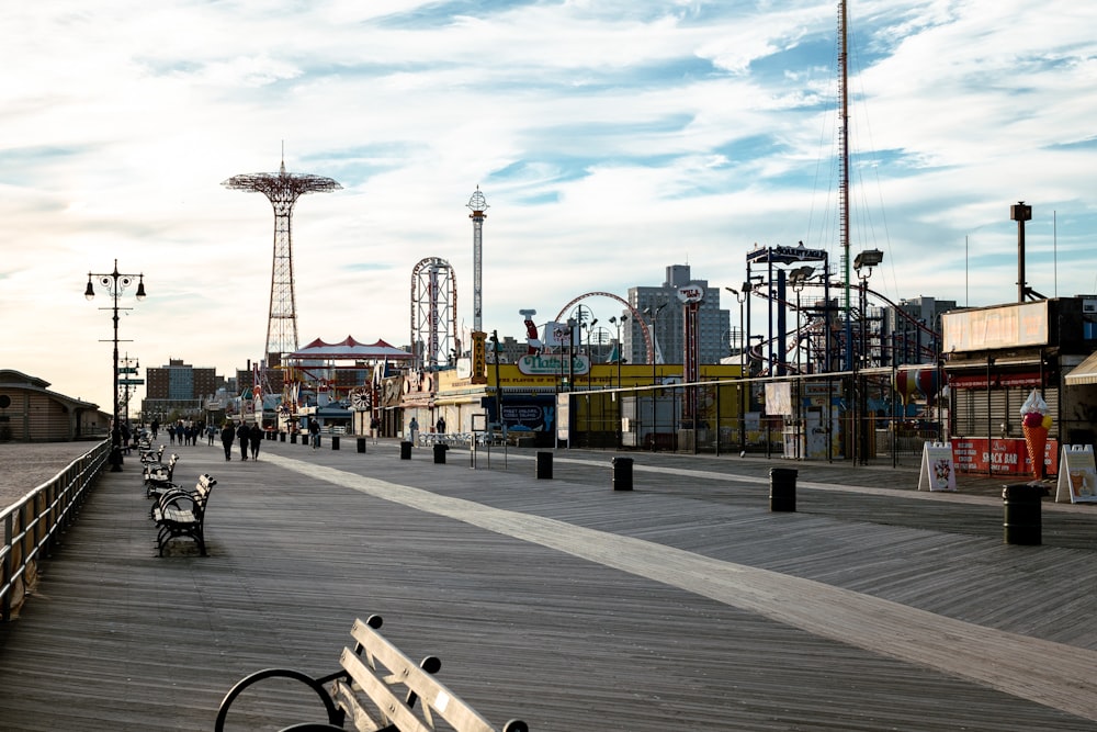 a boardwalk with benches and a roller coaster in the background