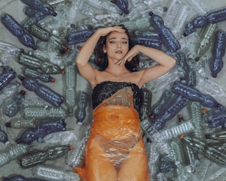 a woman laying on top of a pile of plastic bottles