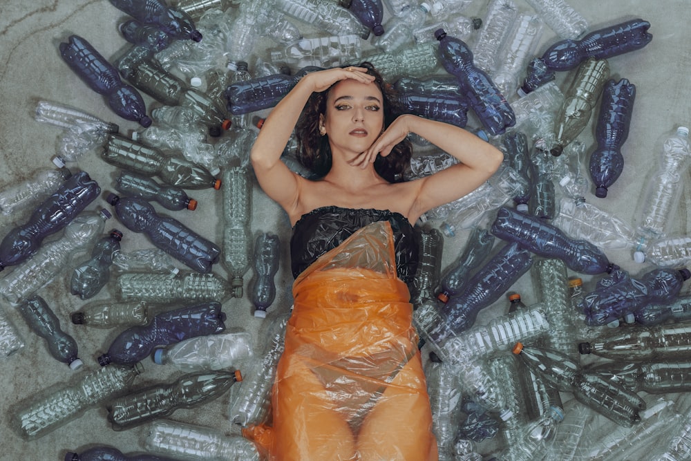 a woman laying on top of a pile of plastic bottles