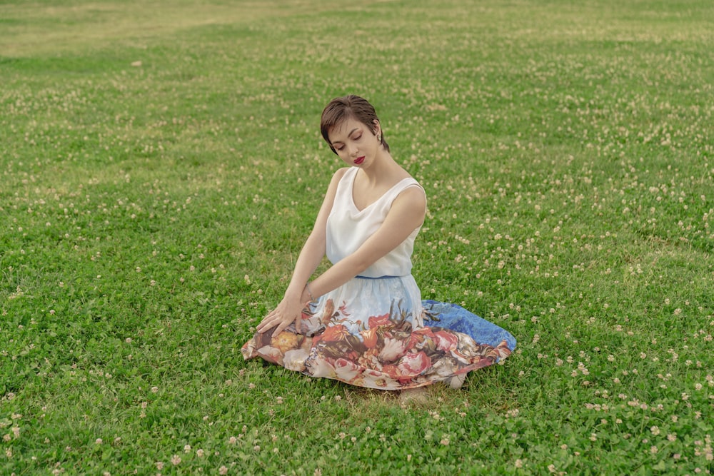 a woman sitting on the ground in a field of grass