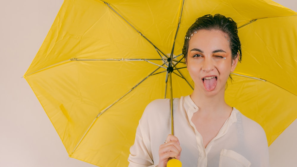 a woman holding a yellow umbrella making a funny face