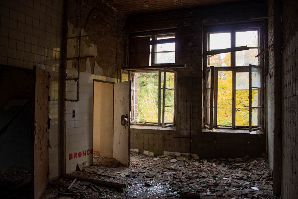 Una habitación deteriorada con ventanas rotas y escombros en el suelo