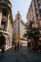a group of people walking down a street next to tall buildings