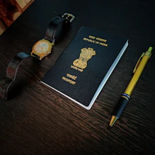 a passport, watch and pen on a table