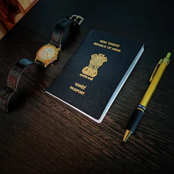 a passport, watch and pen on a table