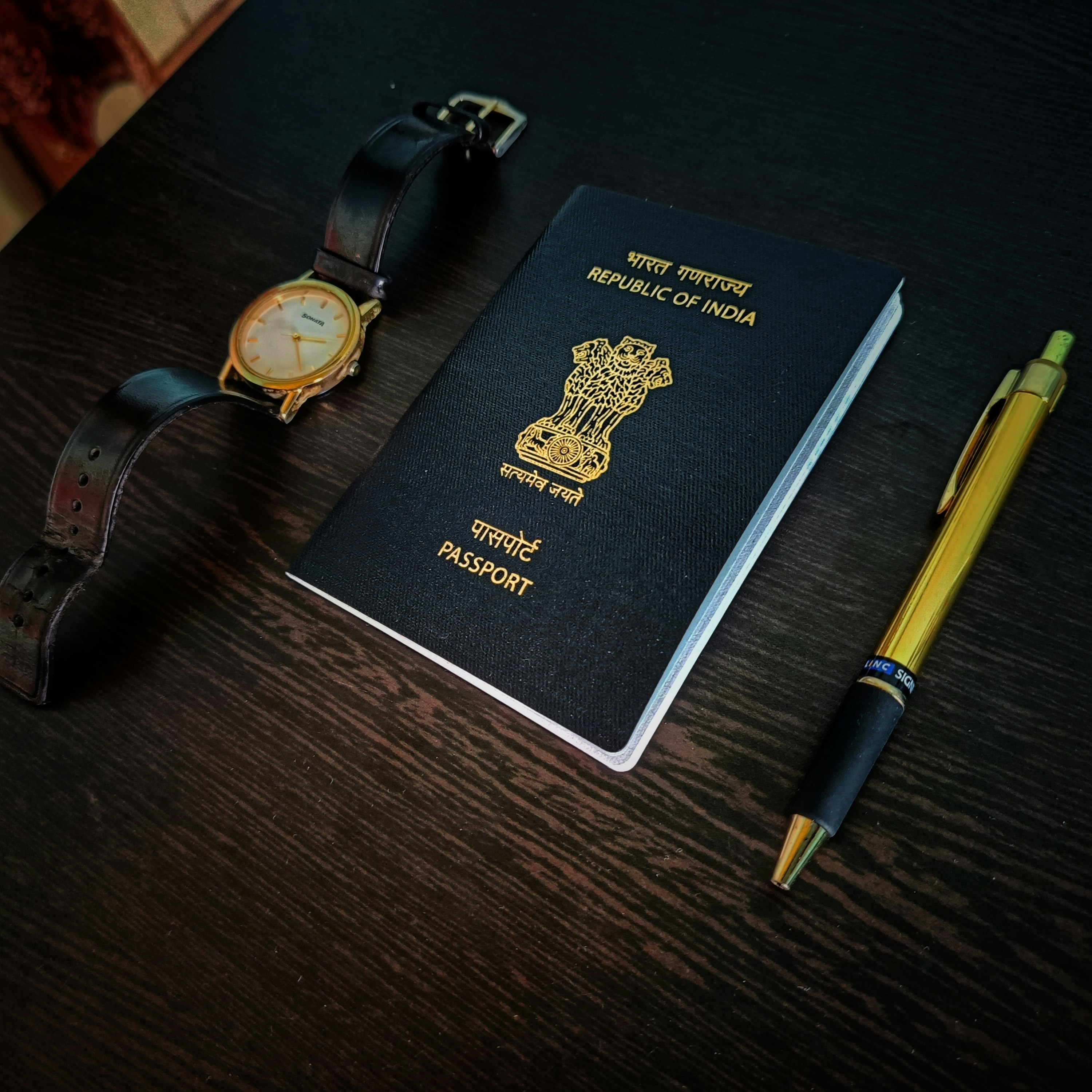 a passport, watch and pen on a table