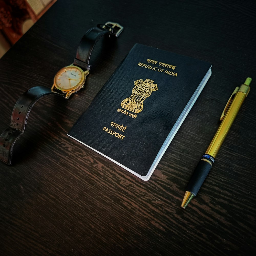 a passport, watch and pen on a table
