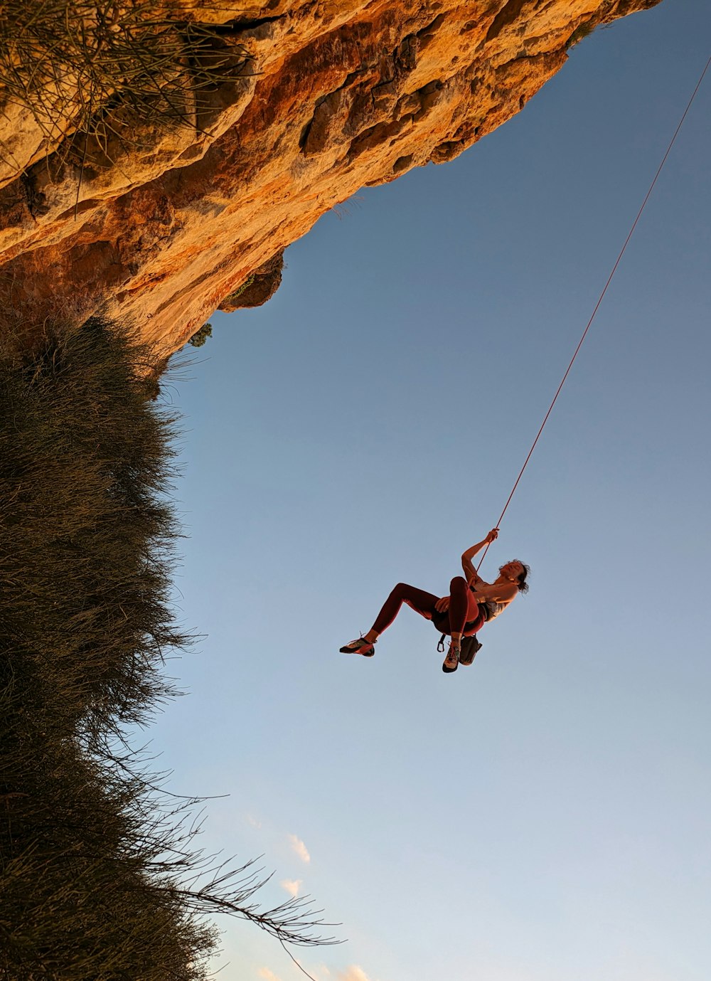 a man hanging from a rope on top of a cliff