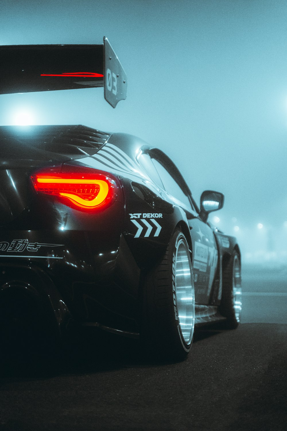 a black sports car with its tail lights on