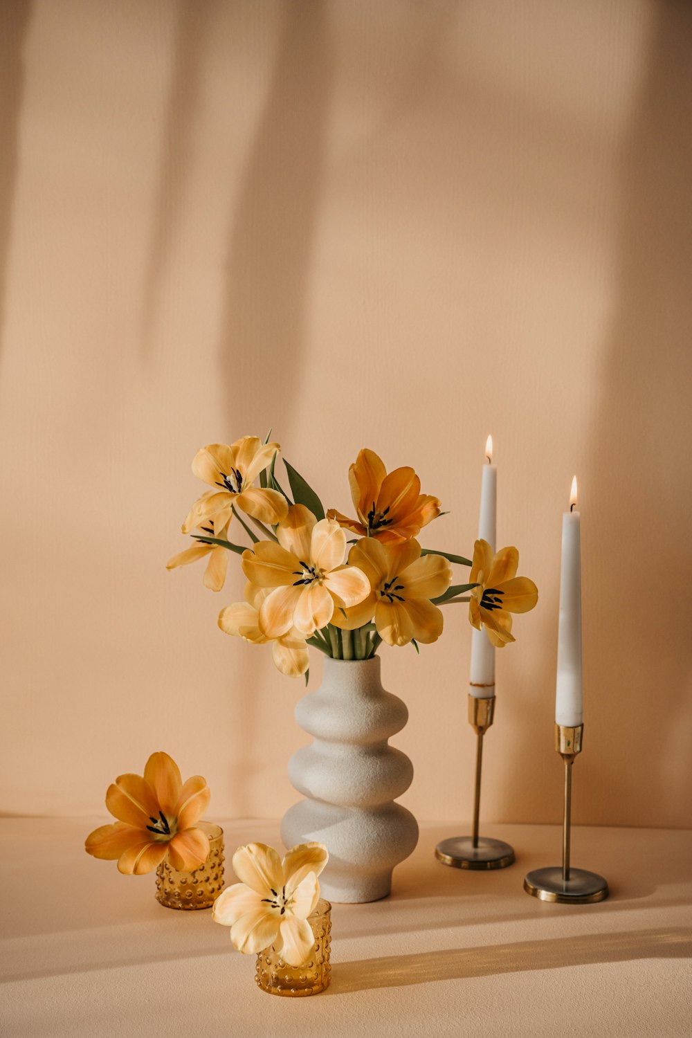 a vase with flowers and candles on a table