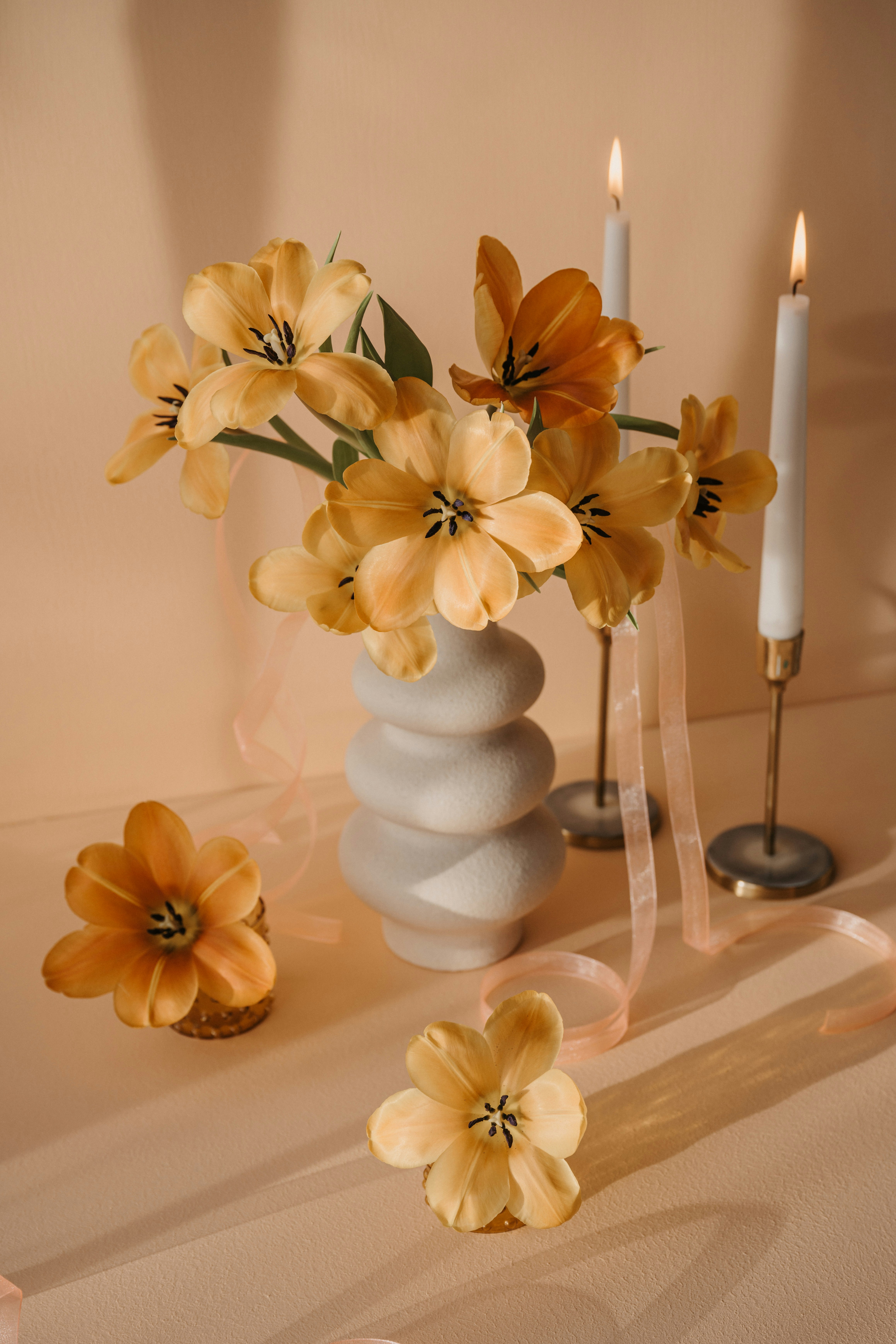 a vase filled with yellow flowers next to a candle