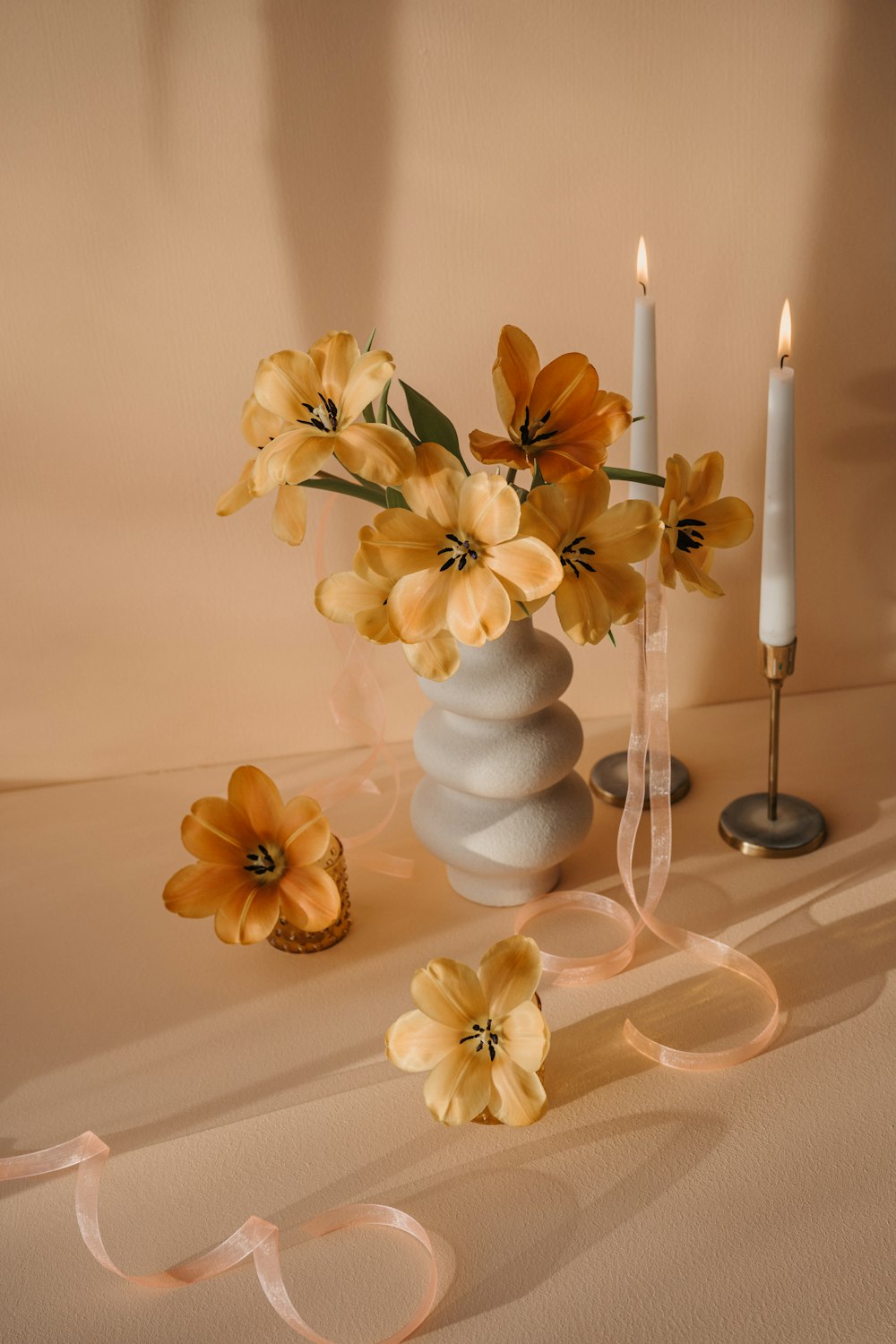a vase filled with yellow flowers next to two candles