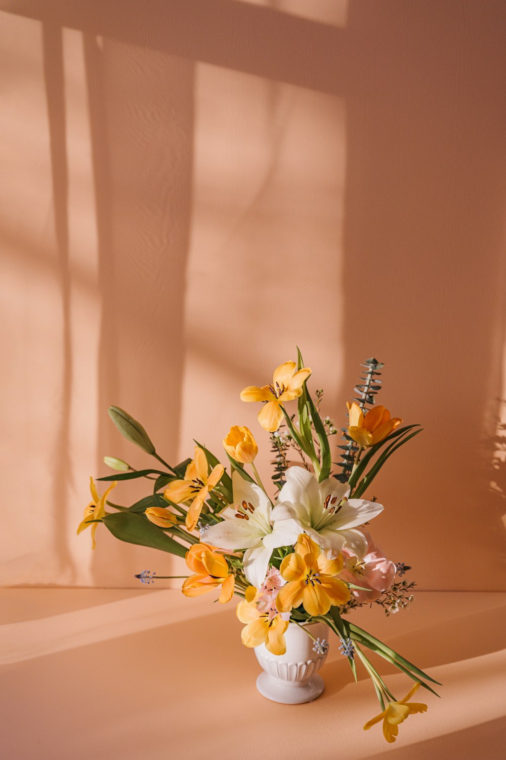 a white vase filled with yellow and white flowers
