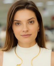 a woman wearing a white top and a gold necklace