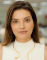 a woman wearing a white top and a gold necklace