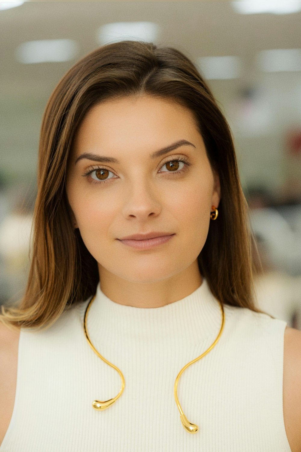 a woman wearing a white top and a gold necklace