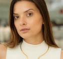 a woman wearing a white top and a gold necklace