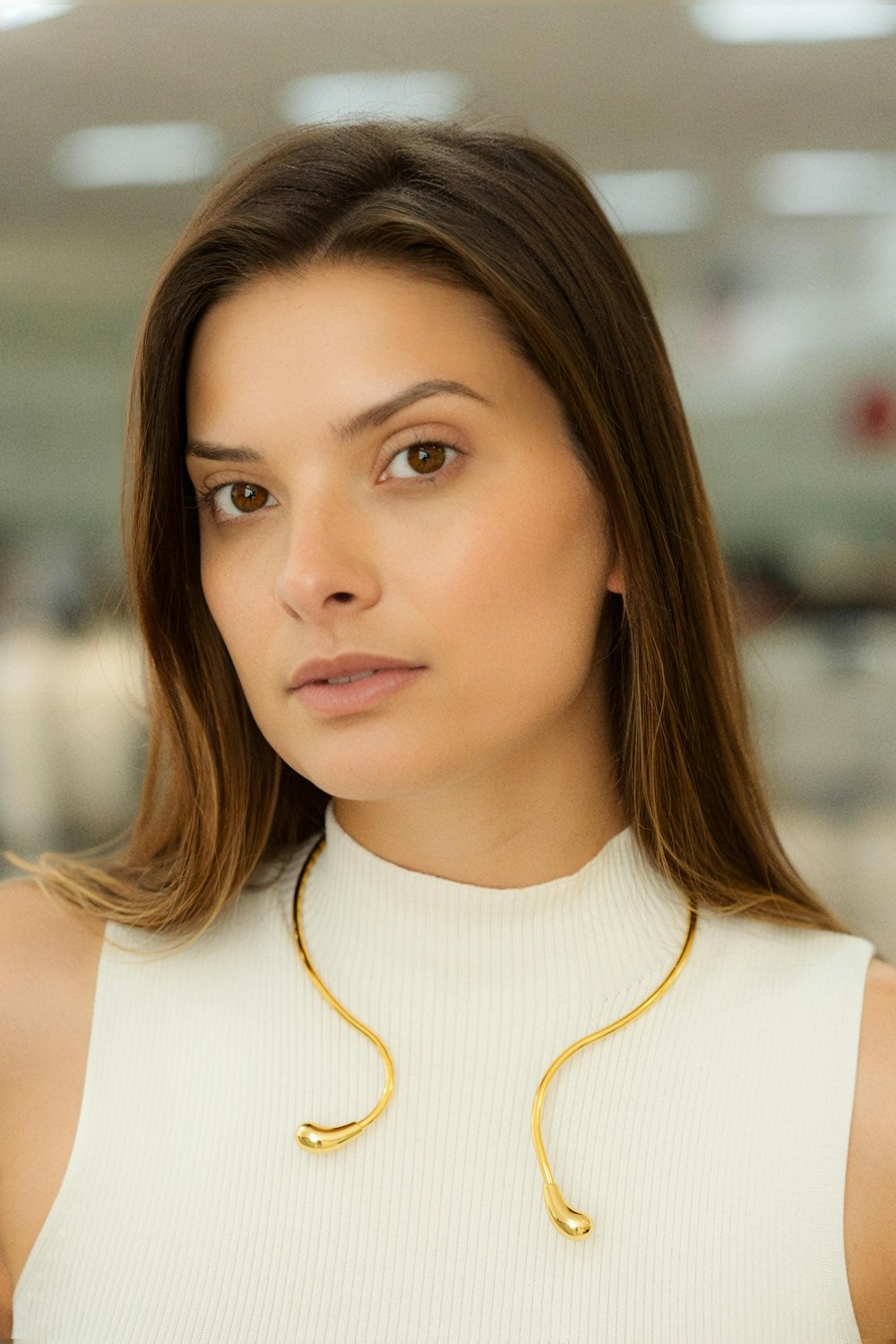 a woman wearing a white top and a gold necklace